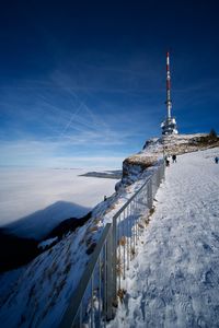 Snow covered land and mountains against blue sky