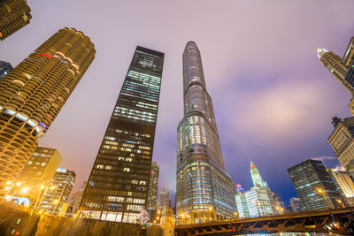 Low angle view of illuminated skyscrapers in city against sky at dusk