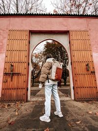 Rear view of man standing on footpath by building