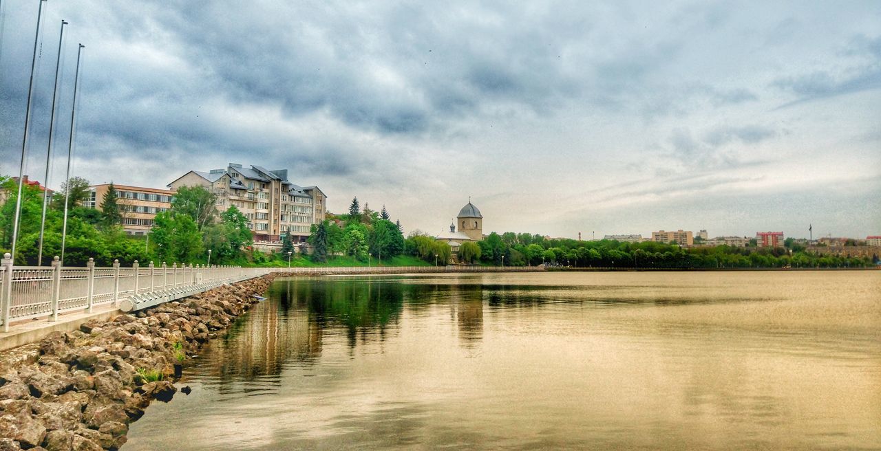 VIEW OF BUILDINGS BY LAKE AGAINST SKY