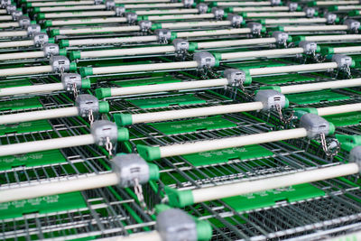 Many empty green shopping carts in row. row of parked trolleys in supermarket.