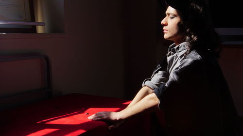 Side view of young man meditating in darkroom