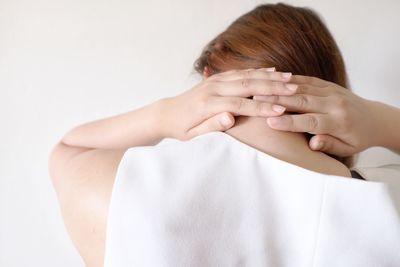 Rear view of a woman covering face over white background