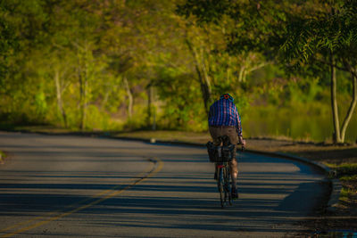 Rear view of man riding bicycle on road