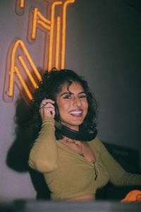 Portrait of happy young female dj with headphones at nightclub