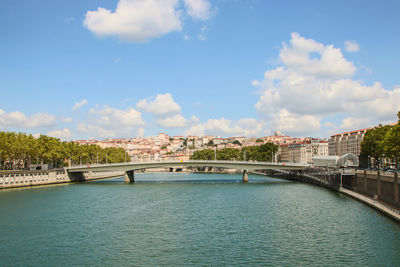 Arch bridge over river in city against sky