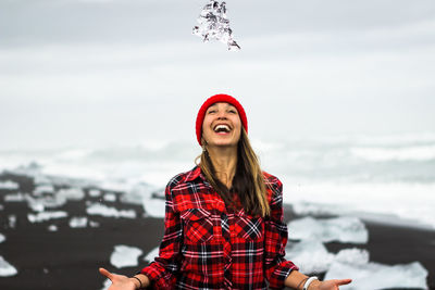 Cheerful woman standing at beach during winter