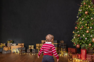 Rear view of girl standing against christmas tree