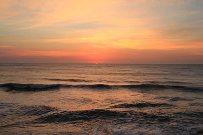 Scenic view of sea against cloudy sky at sunset