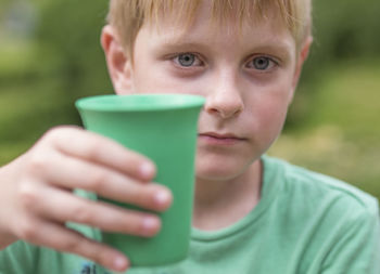 Portrait of boy holding green drinking glass