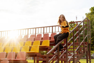 Full length of young woman sitting on escalator