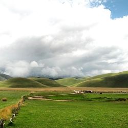 Scenic view of grassy field against cloudy sky