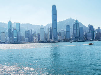 Sea by modern buildings against sky in city