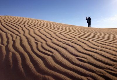 Man photographing in desert against sky