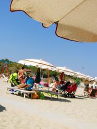 People sitting on beach against clear sky