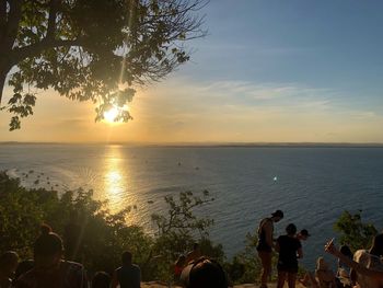 People at beach against sky during sunset