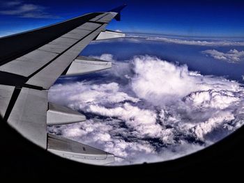 Airplane wing over landscape against blue sky