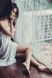 Young woman sitting by window at home