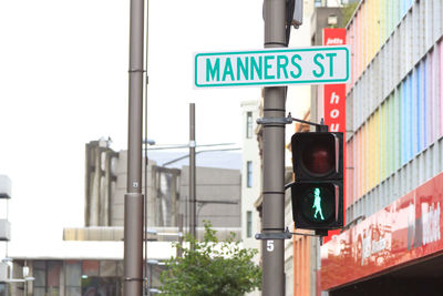 Close-up of road sign against sky in city