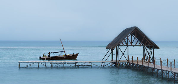 Boat by pier in sea against clear sky