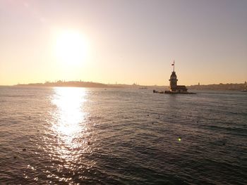 View of lighthouse at seaside during sunset