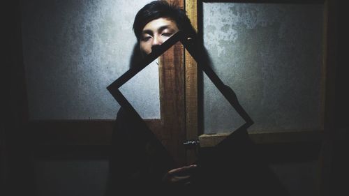 Young man holding mirror indoors