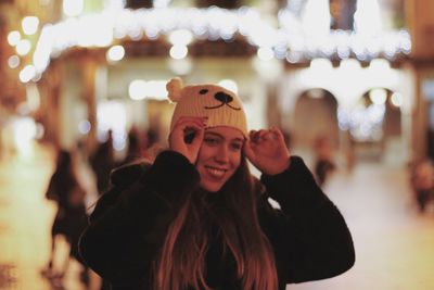 Smiling young woman wearing knit hat at night