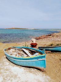 Boat moored on beach against sky