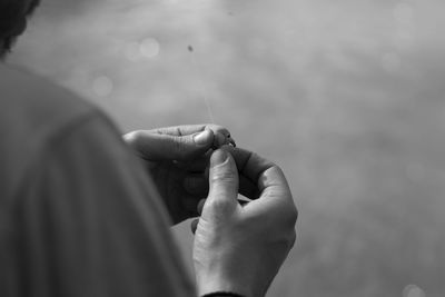 Cropped hands holding fishing bait