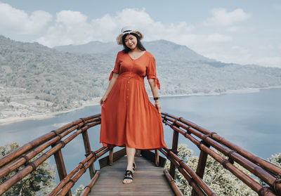 Portrait of woman standing on railing against mountain