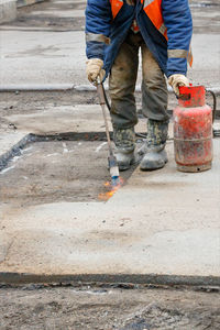 The worker makes preliminary preparations for the repair of the road  using gas burner and propane 