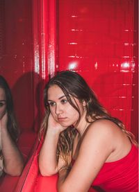 Portrait of beautiful young woman sitting in red room