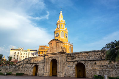 Low angle view of historic clock tower gate against sky