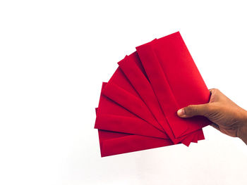 Close-up of hand holding paper against white background