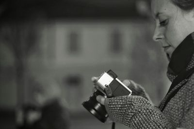 Woman holding camera while standing outdoor