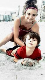 Portrait of young woman sitting on beach in city