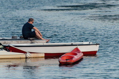 Man sitting on pier over sea