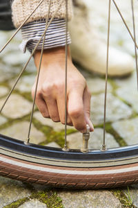 Cropped image of businesswoman checking bicycle tire on sidewalk