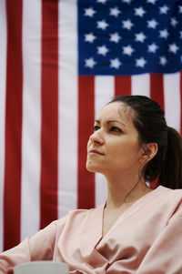 A young girl sitting with the american flag in the background. concept of america