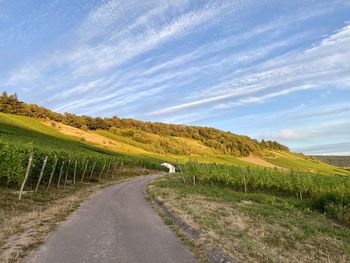 Road amidst field against sky