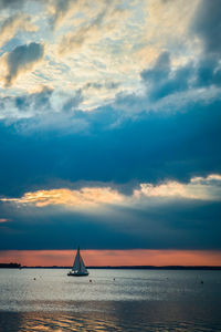 Sailboat sailing on sea against cloudy sky