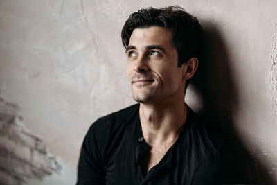 Portrait of young man standing against wall