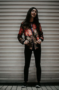 Portrait of young woman standing against wall