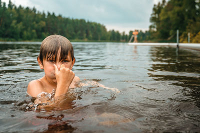 Portrait of shirtless boy swimming in lake