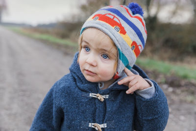 Close-up of cute girl wearing knit hat while standing on dirt road