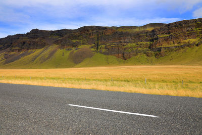 Scenic view of road by mountains against sky