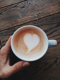 Cropped image of hand holding coffee cup on table