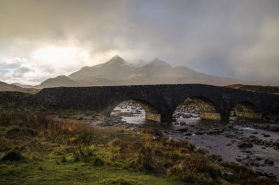Bridge over mountain against cloudy sky