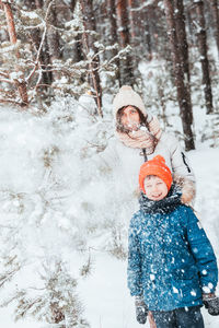 Mom and son play snowballs in the winter forest. mom walks with her son in a snowfall in the forest.