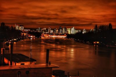 High angle view of illuminated buildings by river against sky